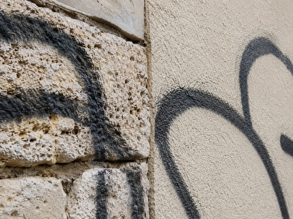 Graffiti sur pierre poreuse et enduit de façade